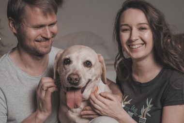 Happy couple playing with their Labrador dog at home, showcasing love and companionship.