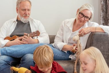 Grandparents playing with grandchildren in a cozy living room setting.